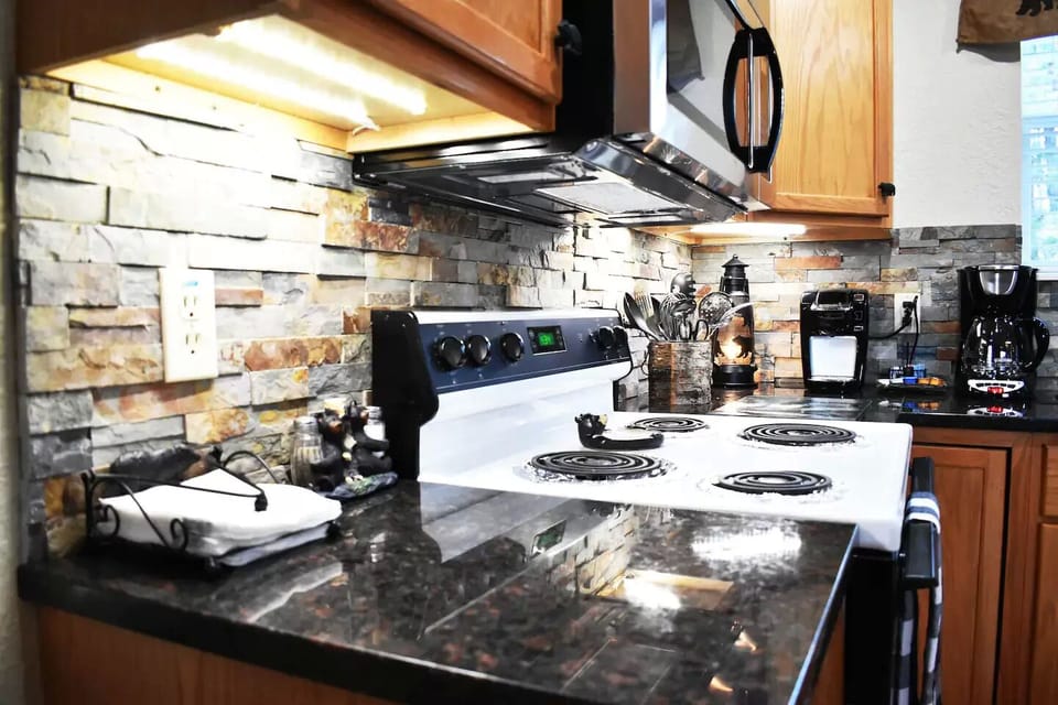 The rock backsplash and granite counter tops add a rustic touch to the kitchen.