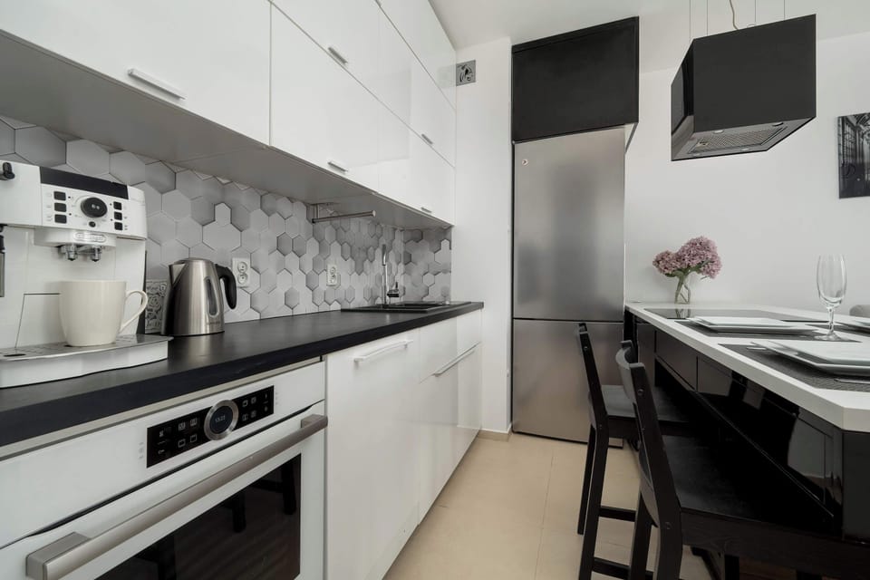 A compact and modern kitchen area with sleek appliances, a tiled backsplash, and plenty of countertop space for meal preparation.