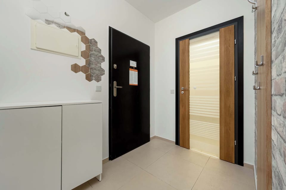 A neat hallway with storage space, wooden doors, and a shoe rack, ensuring functionality and tidiness.