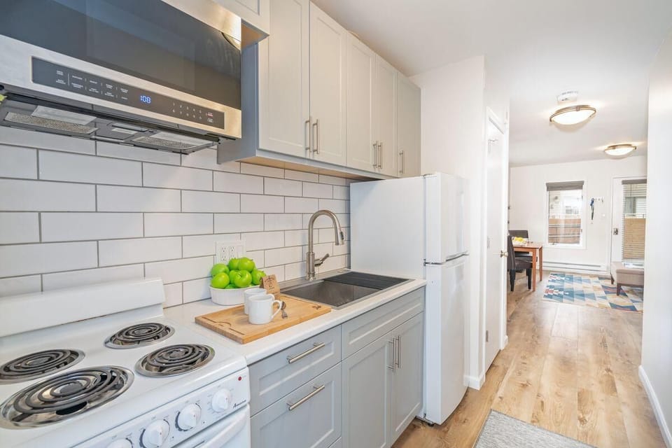 A small but fully equipped kitchen featuring a four-burner mini electric stove, full-size refrigerator, and microwave.