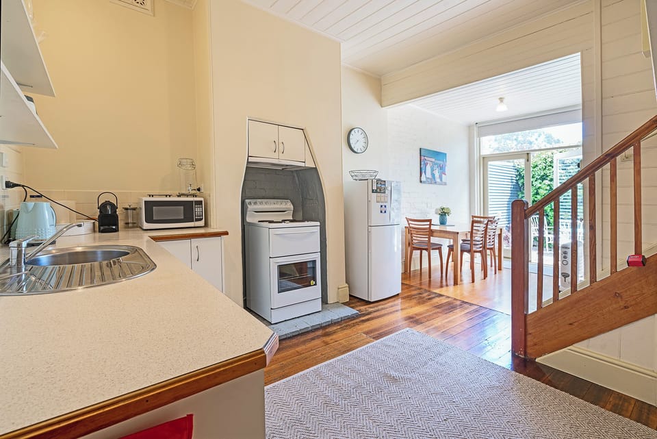 Prepare delicious meals in the well-equipped kitchen, featuring an oven, stove, fridge, and a four-seater dining table. 