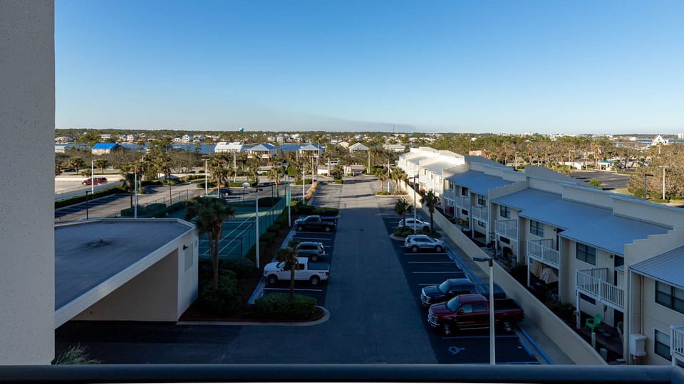 View of the surrounding area featuring palm trees, the tennis court, and view of the bay waters