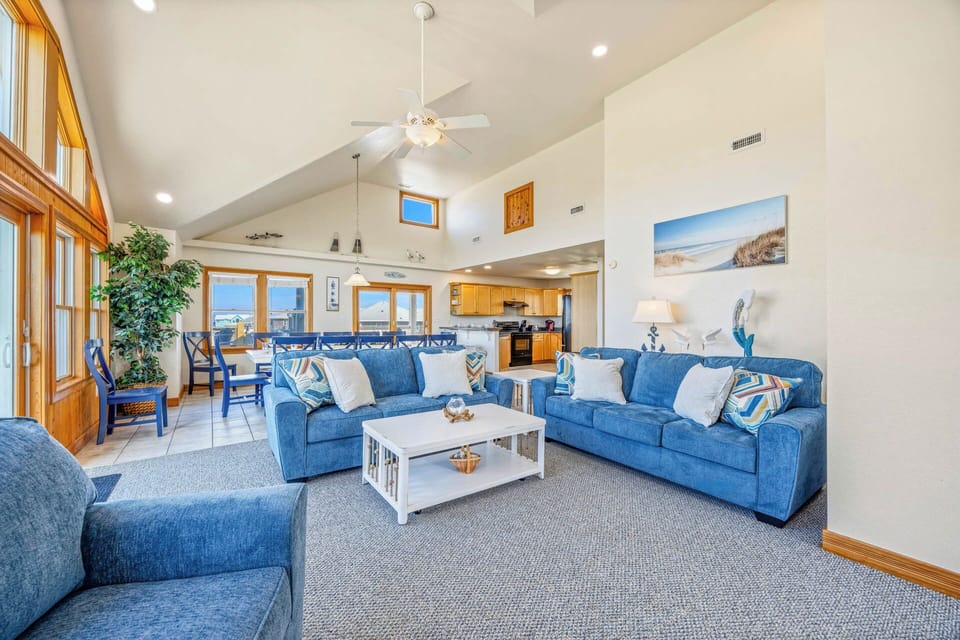 Relax in this bright, open living space with soaring ceilings, coastal blue furnishings, and plenty of natural light to unwind in comfort.