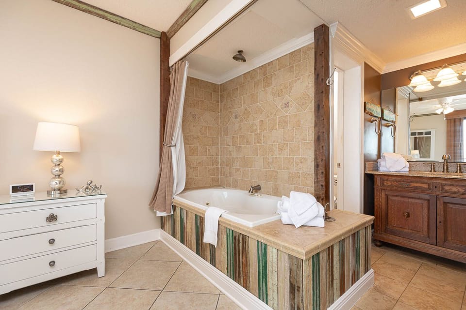 Indulge in relaxation with a spacious jetted tub, stylish decor, and view to the master suite and beachfront balcony