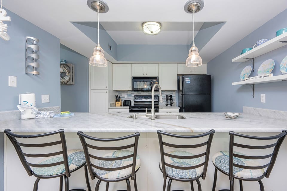 The kitchen features sleek granite countertops, black appliances, and bar seating for a delightful cooking experience