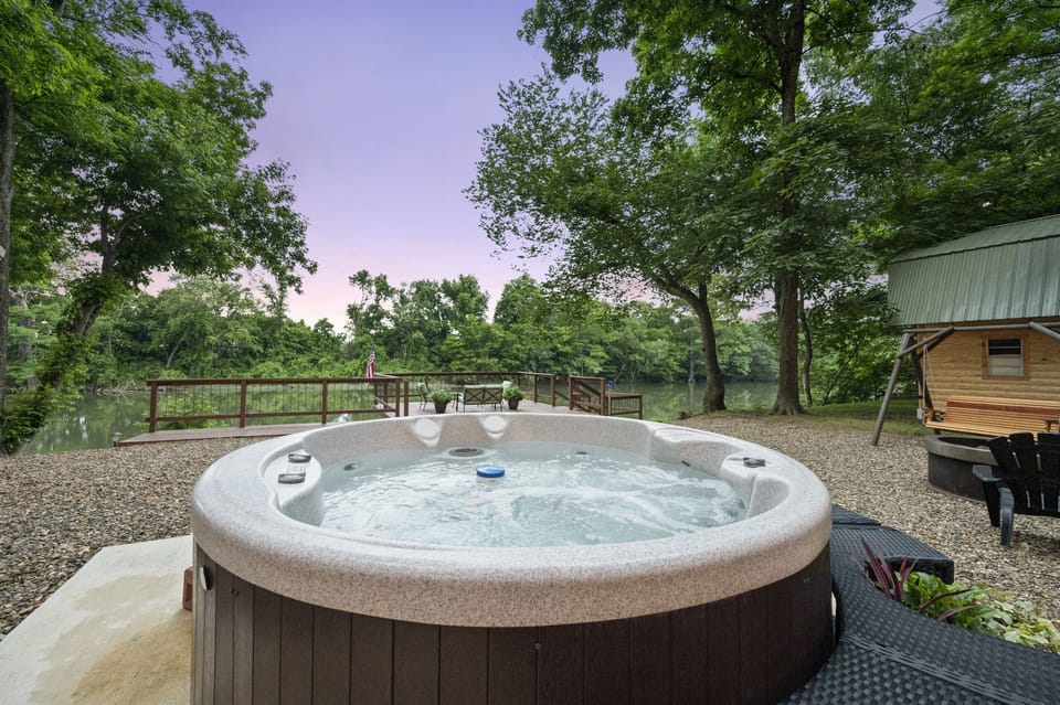 The hot tub sits between the cabin and the fire pit.
