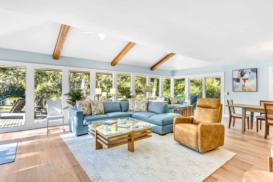 Relax in your bright, airy living space where exposed wooden beams and floor-to-ceiling windows frame garden views perfectly.
