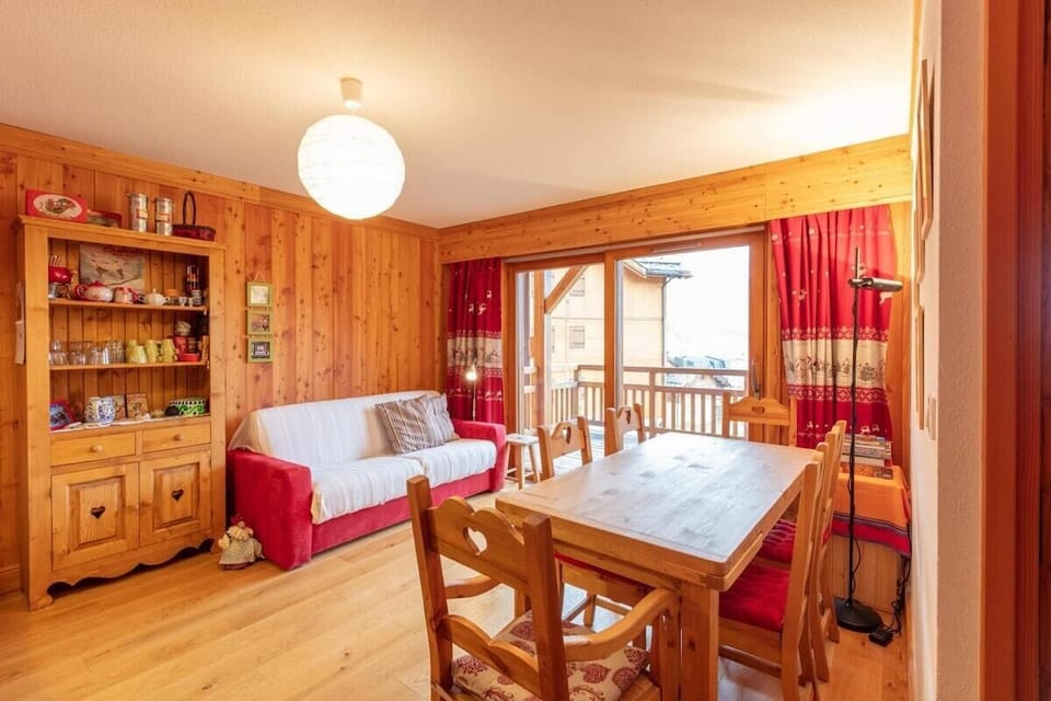 Living area with TV, dining area with table and chairs for 6 people, large patio doors leading to a large, west facing balcony overlooking the piste