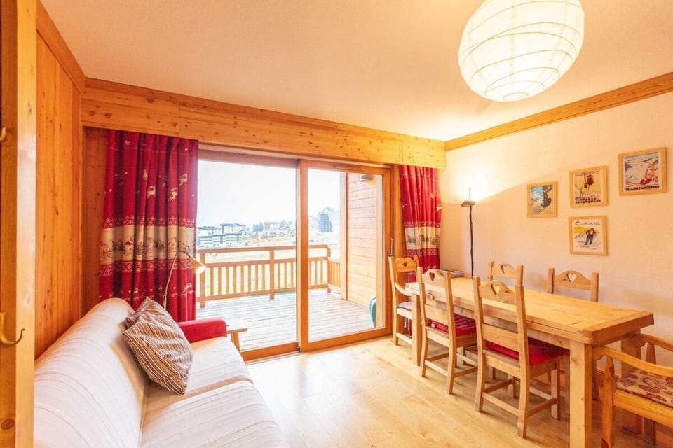 Living area with TV, dining area with table and chairs for 6 people, large patio doors leading to a large, west facing balcony overlooking the piste