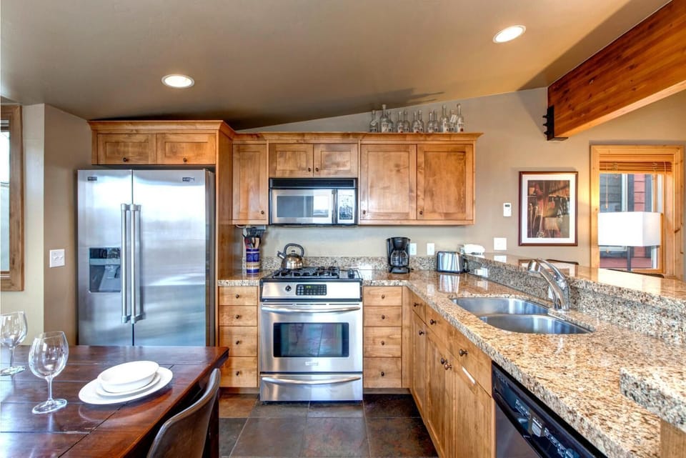Modern kitchen with granite counters, stainless appliances, and wooden cabinetry.