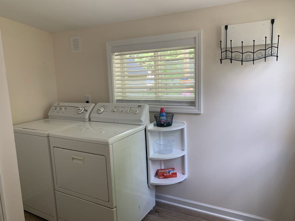 Spacious laundry room with full size washer and dryer, iron and ironing board