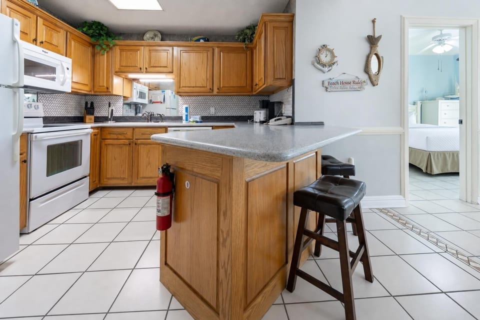 Warm wood cabinetry complements the granite countertop in this inviting kitchen area, featuring a breakfast bar with seating