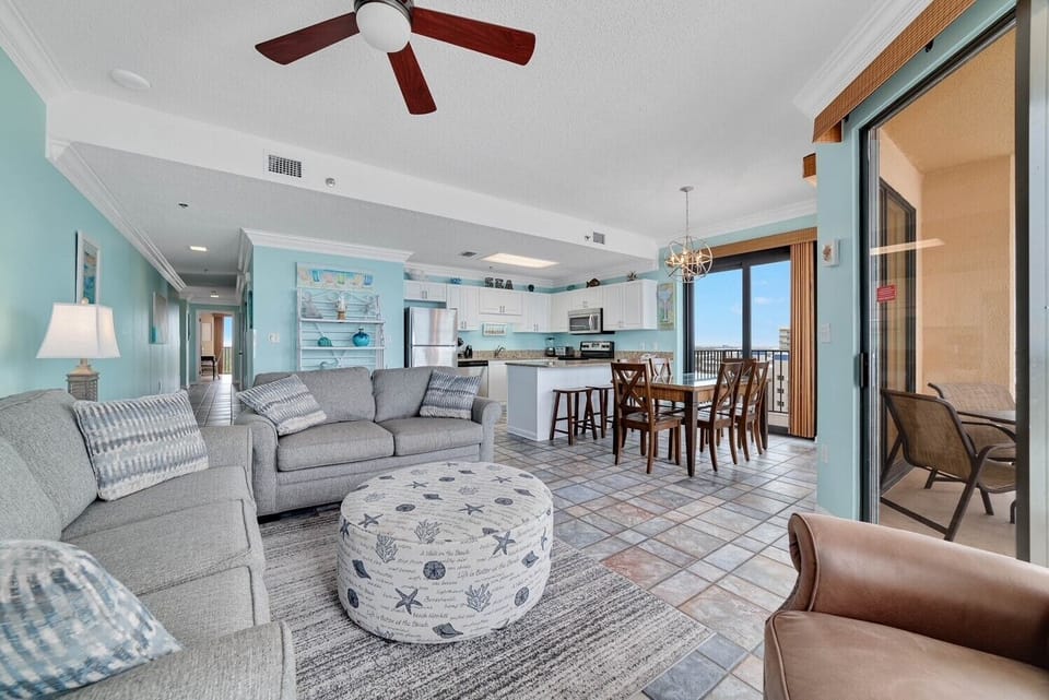 Luminous living area featuring a gray sofa with queen sleeper and a dining table with beach-inspired accents and views