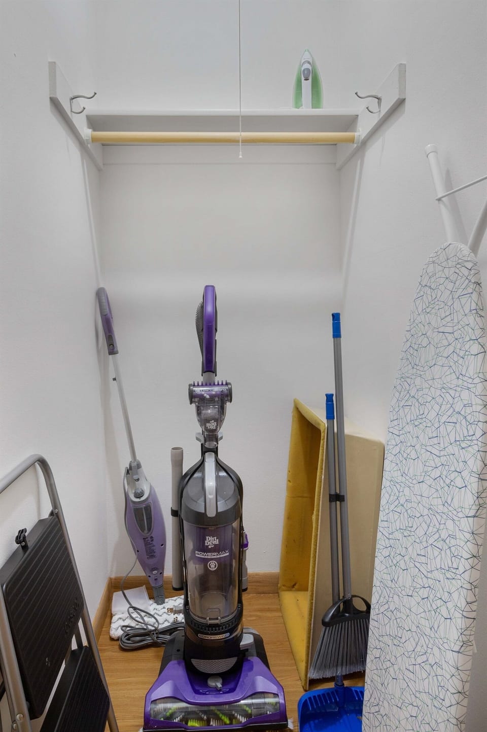 Closet with ironing board, vacuum, steam mop, broom and step stool.