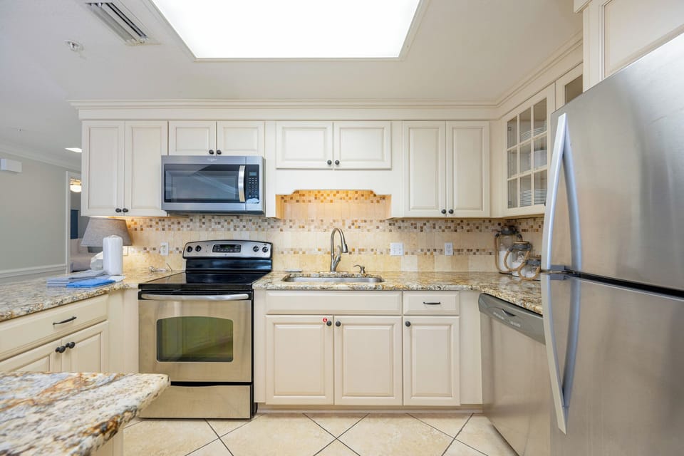 Cream-colored cabinets brighten the kitchen where you gather with family around the granite breakfast bar
