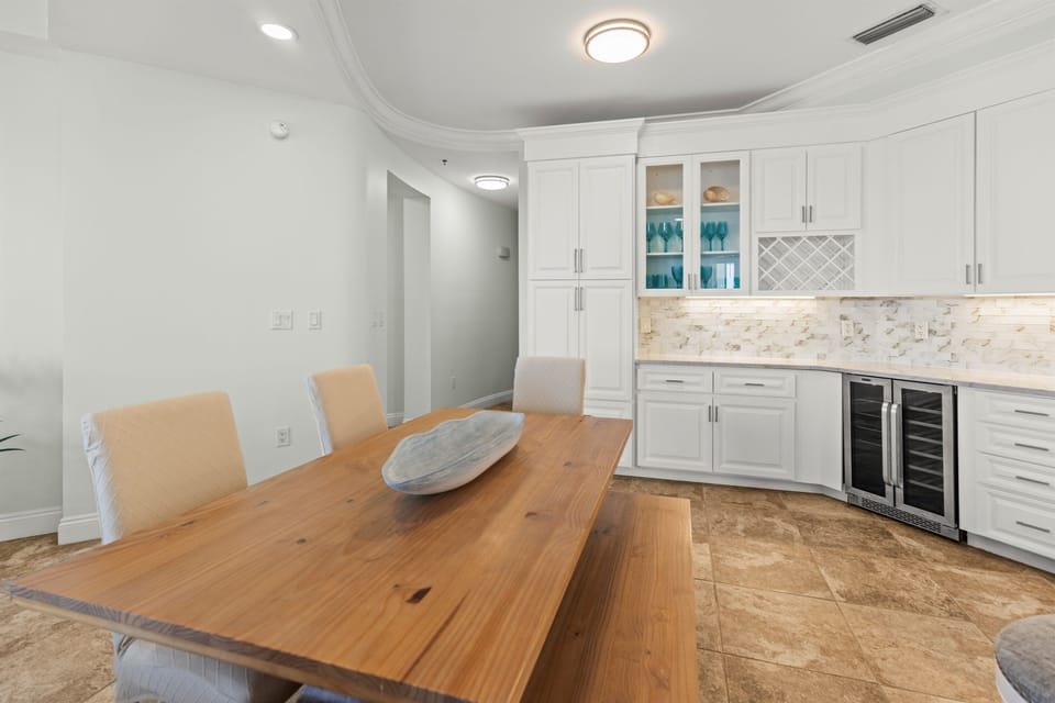 Your elegant dining space features a warm wood table perfect for memorable meals, with sleek white cabinetry and modern appliances ready for your culinary adventures.
