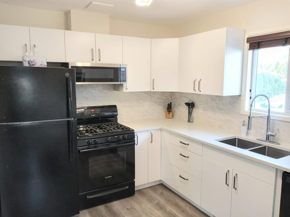 Kitchen with gas stove, fridge, and microwave. 