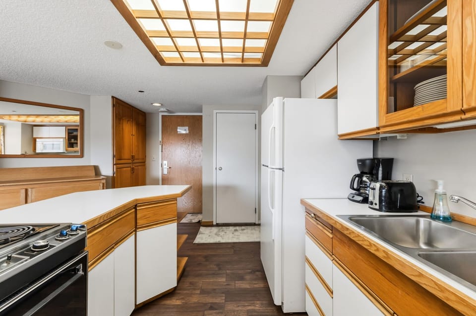 Your fully equipped kitchen features warm wood accents and a stunning skylight that bathes your cooking space in natural light.
