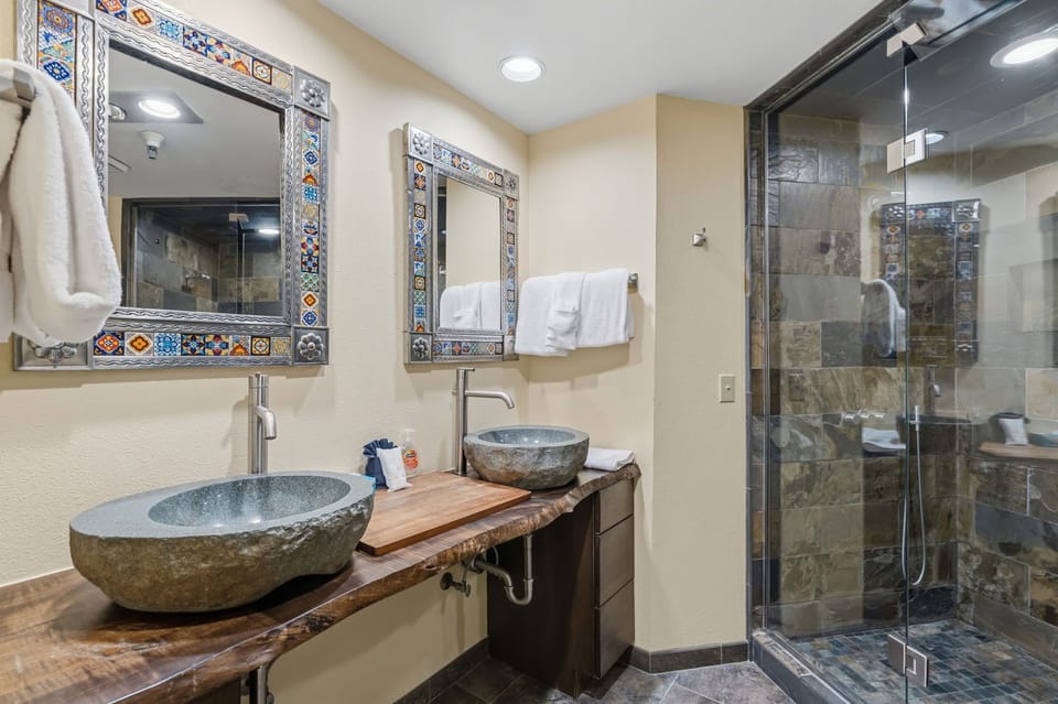Unwind in your artisan-inspired bathroom, where hand-carved stone sinks and colorful tiled mirrors set a welcoming, serene mood after a day of adventure.