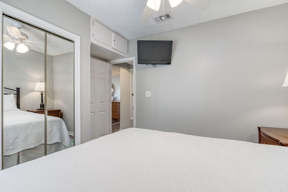 Light and bright second bedroom has a queen bed, flat screen TV and storage!