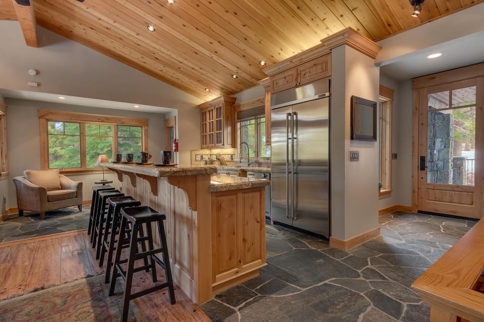- Gourmet kitchen with stainless steel fridge and stove  
- Cabin rental with stone flooring and rustic finishes  
- Tahoe mountain home with open kitchen and seating