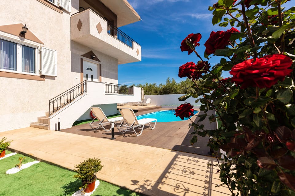 Sunbeds on wooden floor in front of the pool