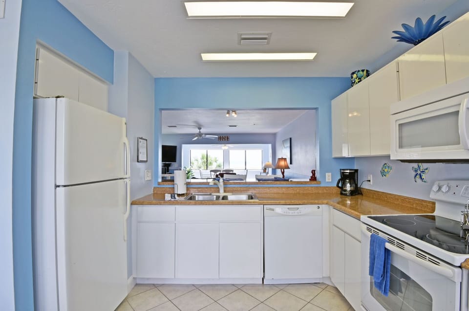 Kitchen open to hallway with white cabinetry and appliances