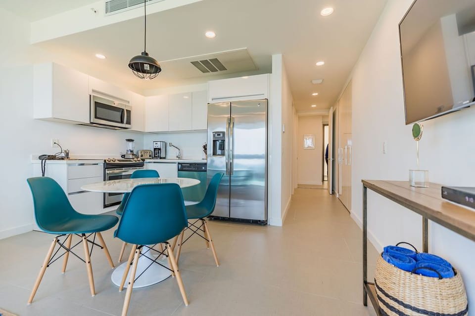 Step into your bright, modern kitchen and dining area—perfect for preparing meals and gathering around the sleek table with your travel companions.