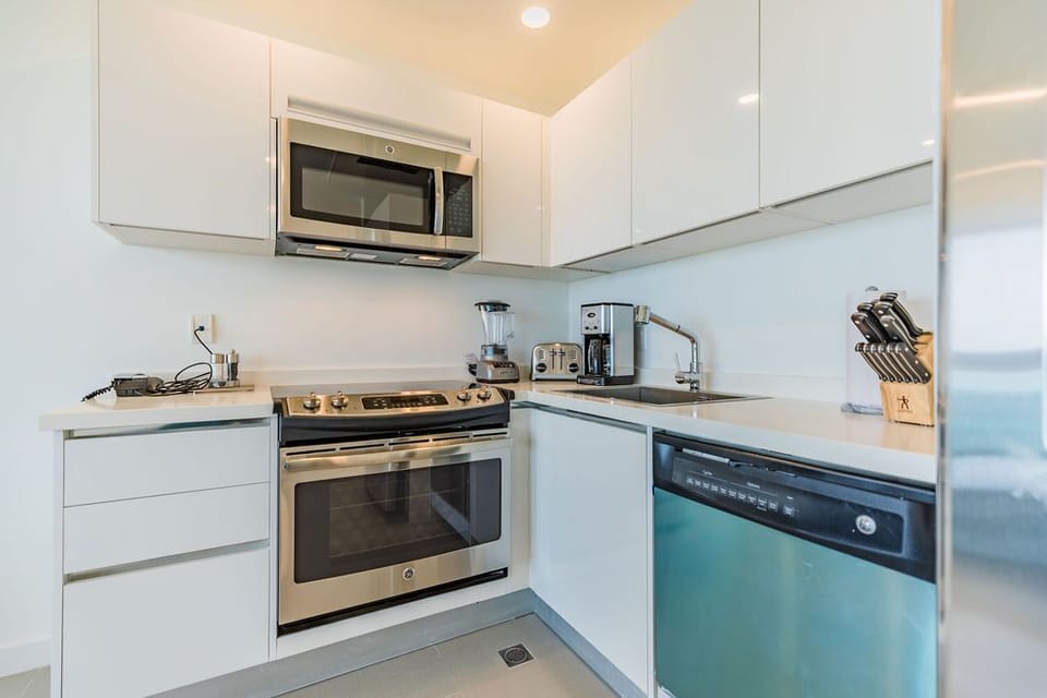 Your fully-equipped kitchen features sleek modern appliances, a stainless steel stove, microwave, blender, and coffee maker—everything you need to cook, relax, and unwind in style.