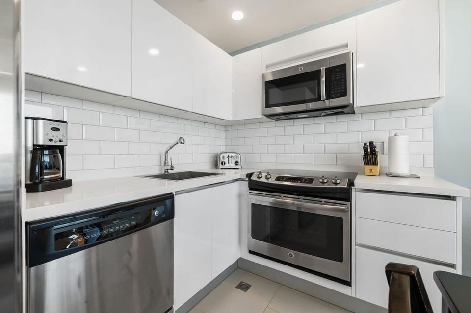 This modern, fully equipped kitchen has everything you need for your stay—prep meals, brew coffee, and enjoy the sleek, clean design with stainless steel appliances and crisp white finishes.