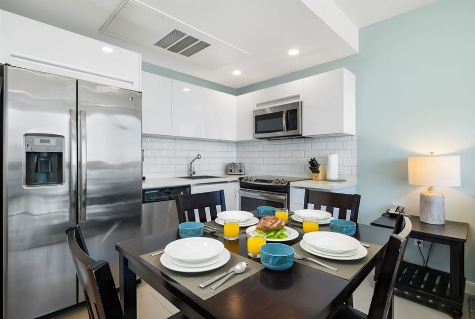 Modern, fully-equipped kitchen with stainless appliances and cozy dining table set for your morning coffee and fresh pastries.