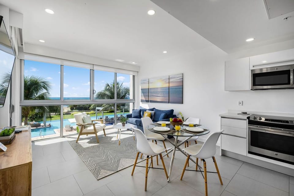 Step into a bright, modern space where living and dining flow seamlessly together, with sparkling pool views and ocean beyond through expansive windows inviting natural light to fill your days.