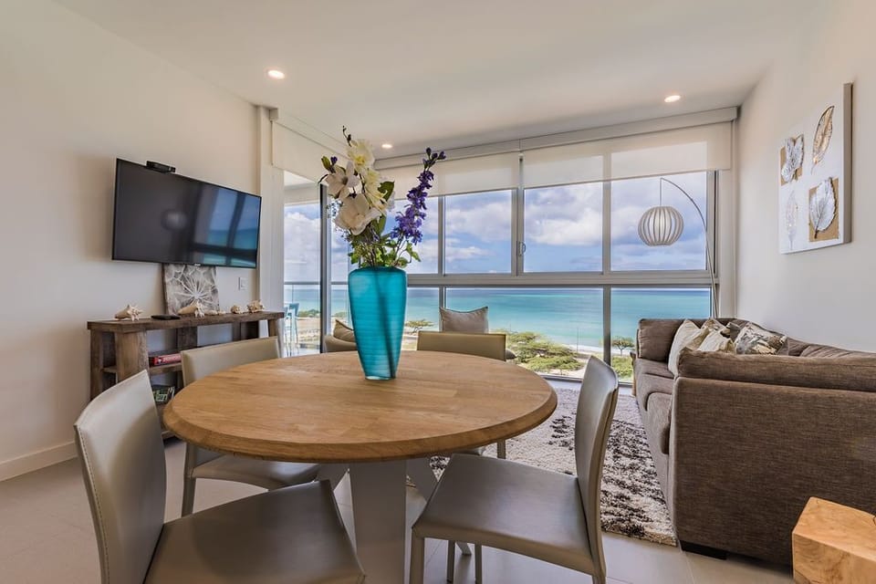 Unwind in your bright, modern living and dining area with stunning turquoise ocean views stretching to the horizon—perfect for morning coffee or evening relaxation.
