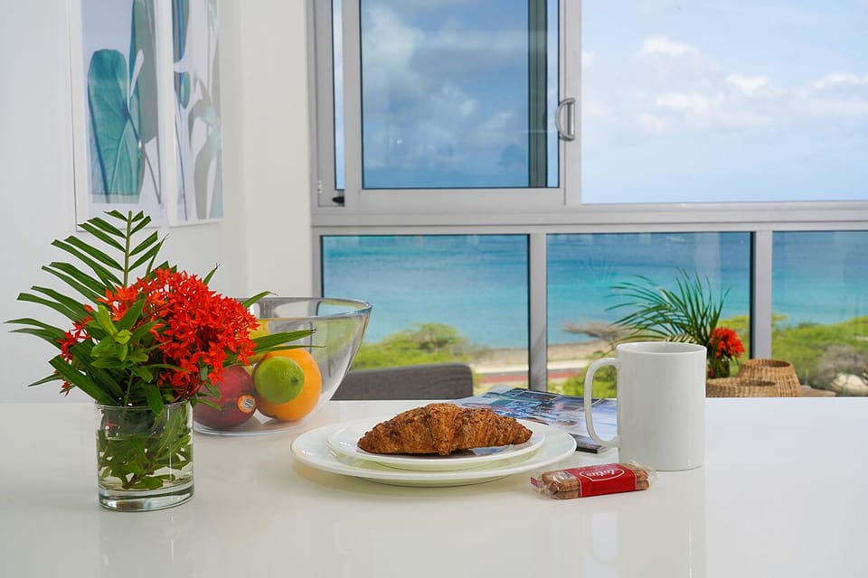 Start your morning with a delicious croissant and coffee at your table, while soaking in breathtaking turquoise ocean views framed by tropical flowers.