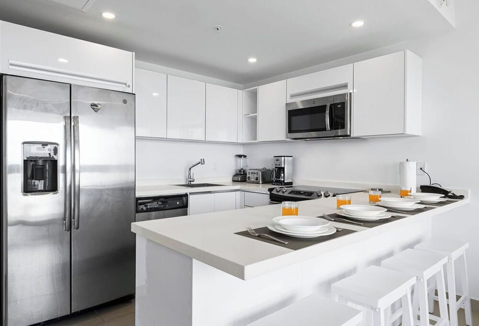 Your sleek kitchen features stainless steel appliances, white quartz counters, and an island breakfast bar set for shared meals and easy entertaining.