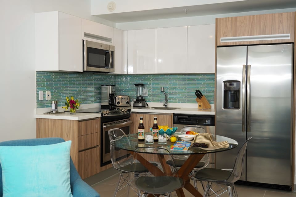 Your fully-equipped kitchen features gleaming stainless-steel appliances, a stunning turquoise tile backsplash, and a stylish breakfast table—perfect for preparing your favorite meals.