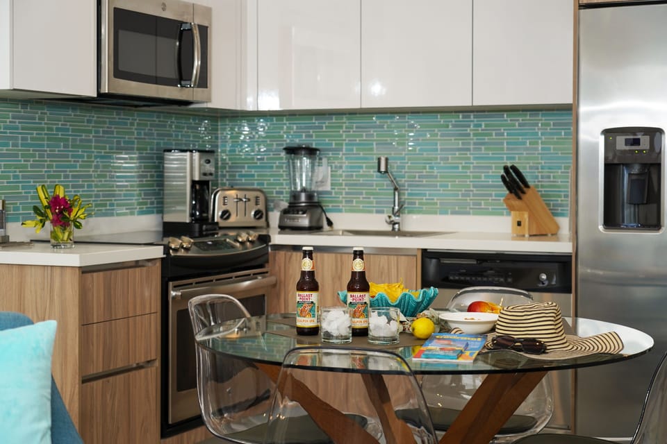 Step into your fully-equipped kitchen, styled with coastal charm and modern convenience. Vibrant turquoise backsplash, stainless appliances, and everything you need to whip up meals or morning coffee.