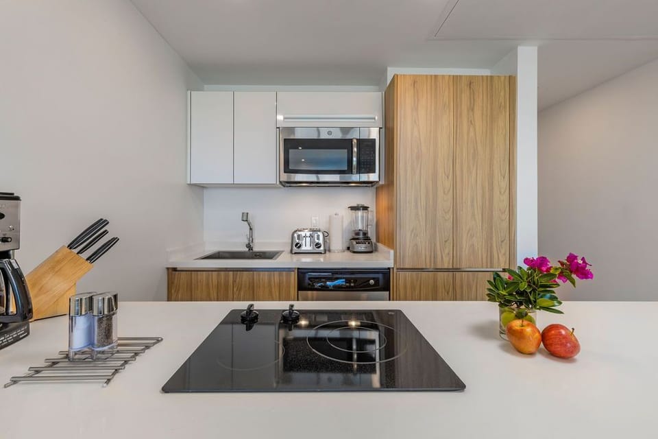 Your sleek kitchen features modern appliances, a stylish induction cooktop, and a warm wood-toned backsplash—ideal for preparing your favorite meals in style.