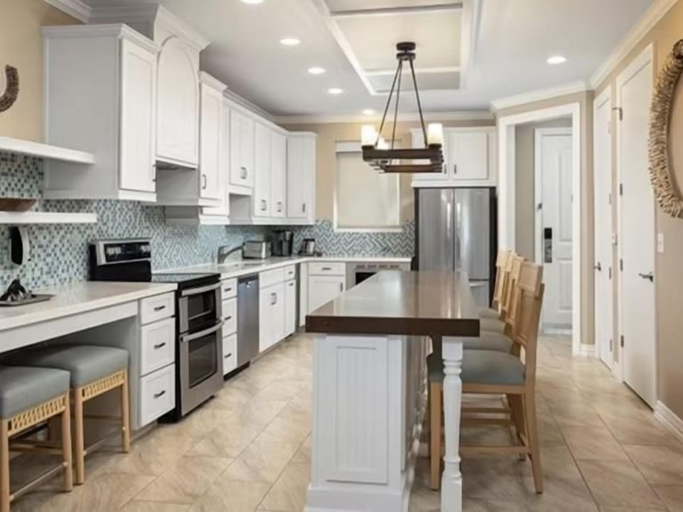 Light-filled kitchen with blue tile backsplash, stainless appliances, and plenty of prep space