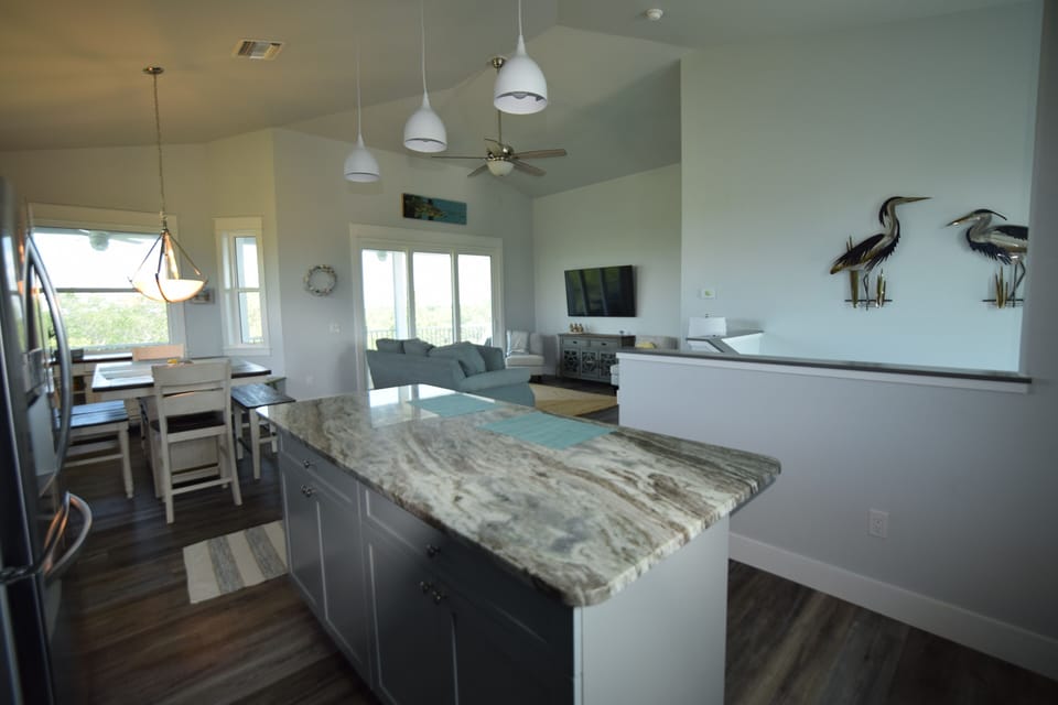 View from kitchen into family room and dining room; metal birds over stairway