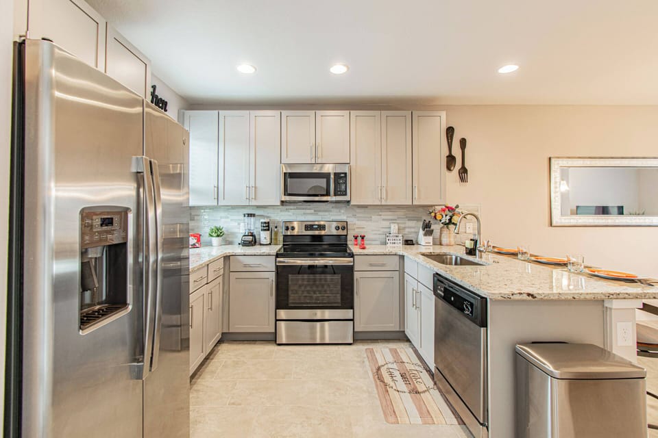 This modern kitchen boasts stainless steel appliances and a spacious countertop, ideal for meal prep or casual breakfasts. The light cabinetry and warm tones enhance the inviting atmosphere for your culinary adventures.