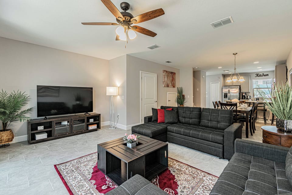 Experience a cozy living area filled with rich textures, where a sleek black sectional and elegant coffee table invite relaxation. Natural light enhances the tasteful decor, creating a welcoming atmosphere for your stay.