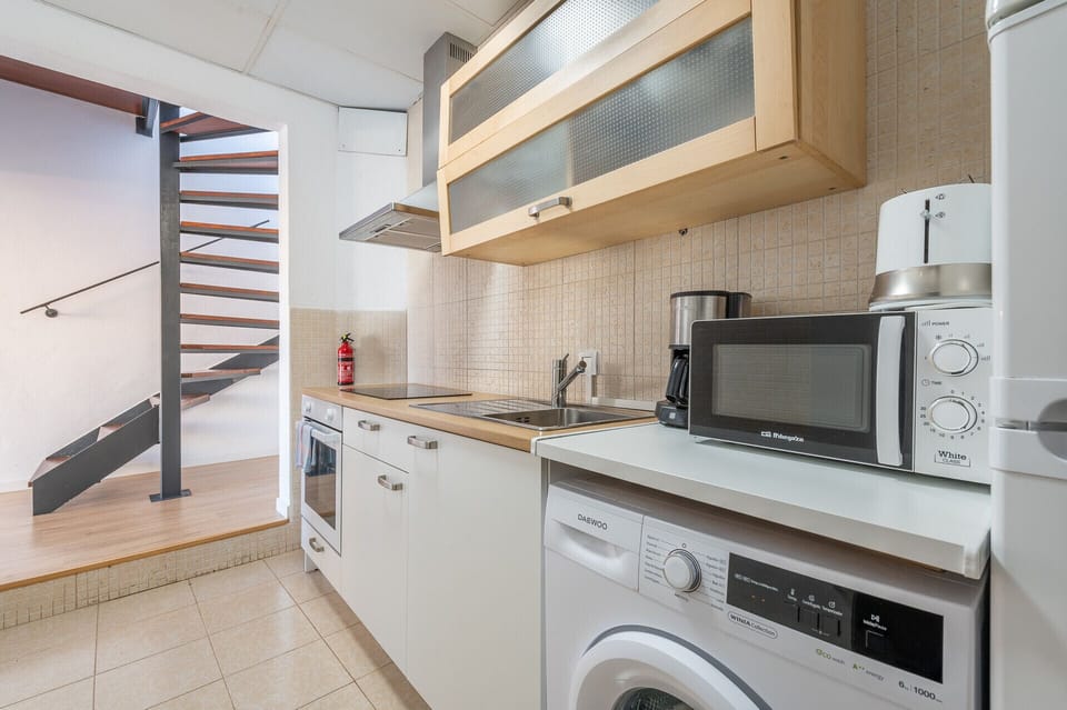 The fully equipped kitchen at Holiday Palma Terrace Apartment has an oven, microwave, coffee maker, kettle, kitchen utensils and washing machine.