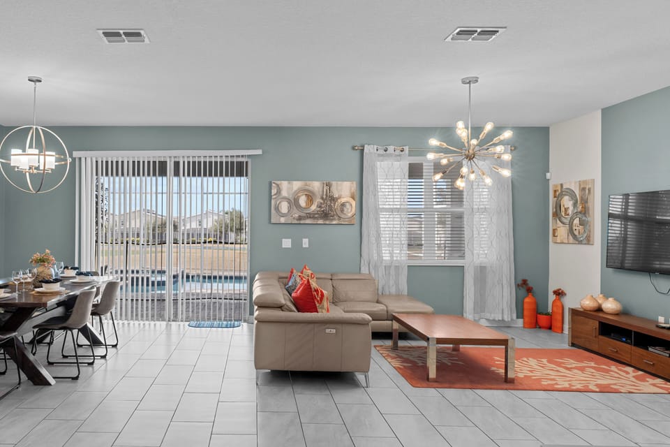 Relax in your spacious open-concept living area with modern furnishings, stylish decor, and peaceful pool views through sliding glass doors.