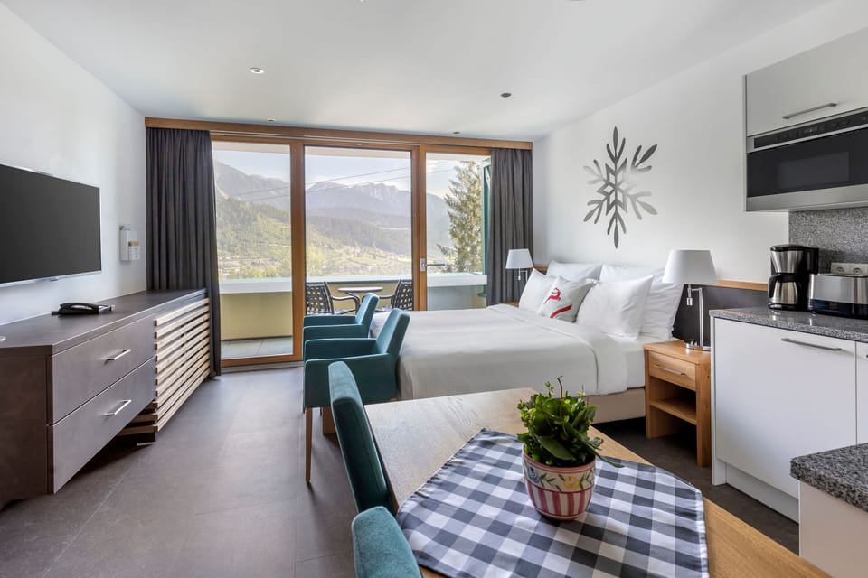 Comfortable studio layout with large windows, mountain views, and modern furnishings.