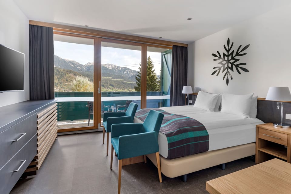 Cozy sleeping area with double or twin beds, balcony access, and scenic forest or mountain views.