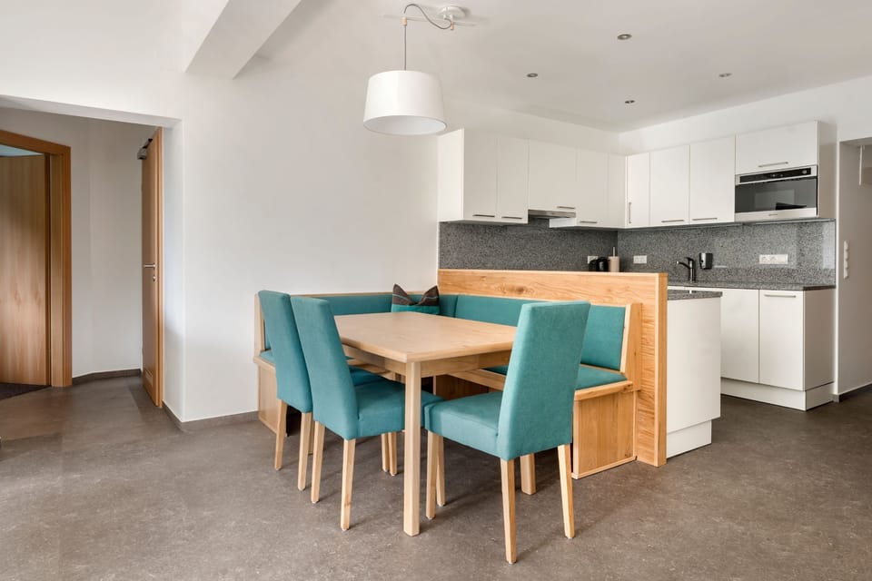 A charming dining nook with a wooden table and teal seating is seamlessly integrated into the open-concept living space, allowing for relaxed meals with family or friends.