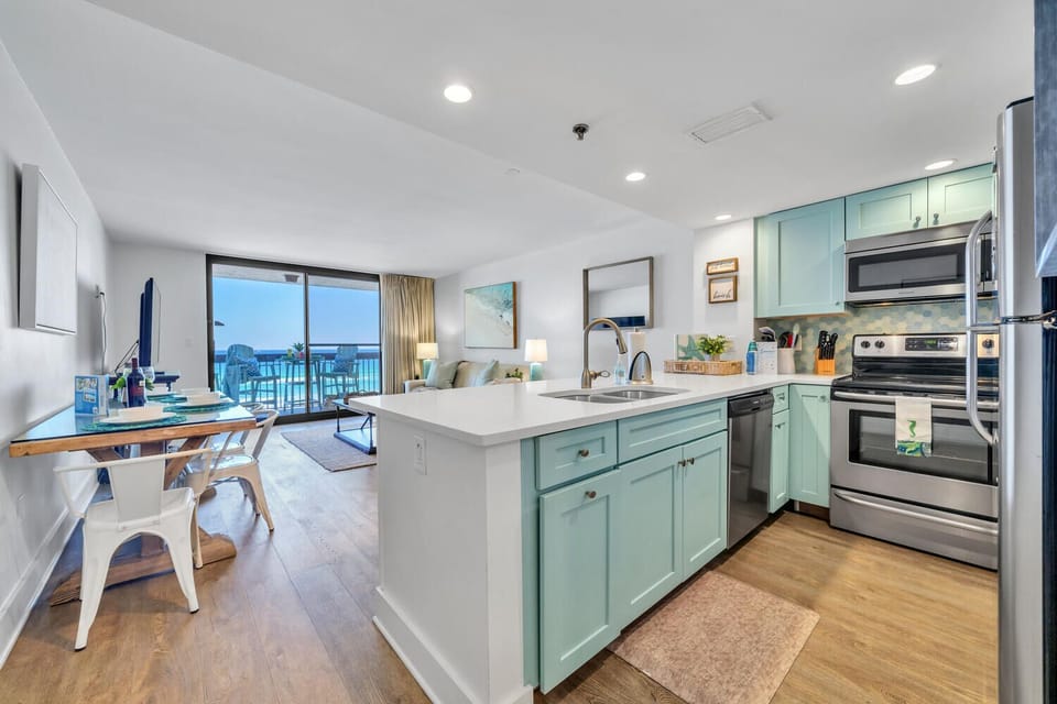 Your bright, modern kitchen flows seamlessly into the living space, where turquoise cabinets and stainless appliances await your culinary adventures.