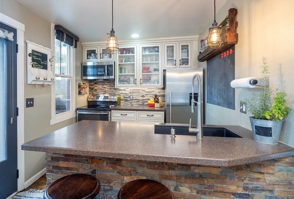 This charming kitchen with a breakfast bar is fully equipped with a refrigerator, oven, microwave, and dishwasher.
