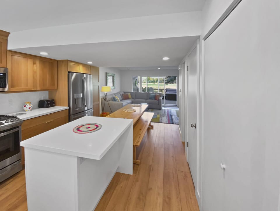 Enjoy a seamless stay in our open-concept living space, featuring a modern kitchen island and a large dining table with benches, perfect for gathering and relaxing.